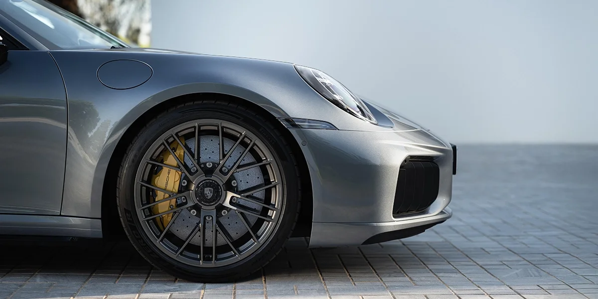 Close-up of 2026 Porsche 911 Turbo S front wheel with carbon ceramic brakes, yellow Porsche calipers, and 20-inch alloy rims.